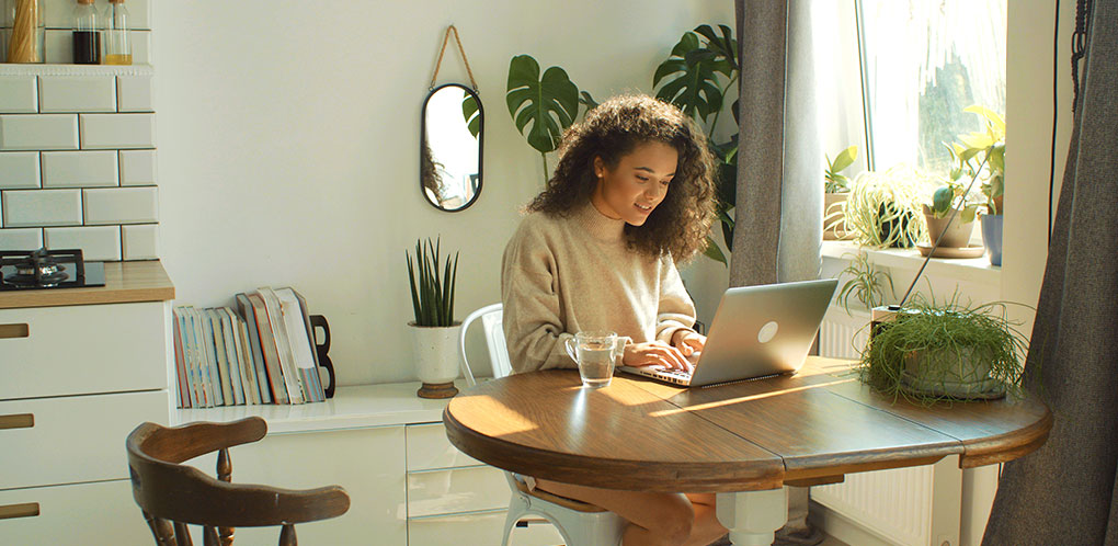 Woman using computer at kitchen table