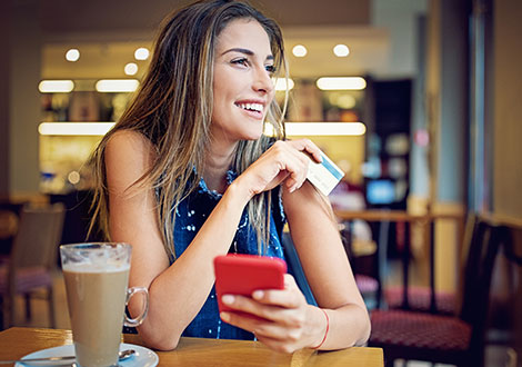 Woman using debit card at coffee shop
